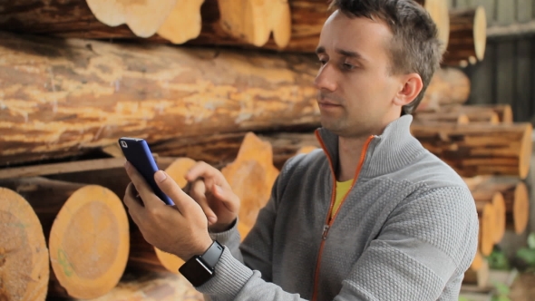 Young Man Forestry Engineer Touch Phone In Front Of Wood
