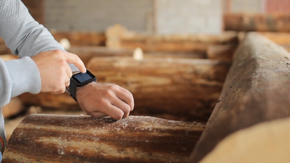 Young Man Forestry Engineer Touch Smart Watch In Front Of Wood