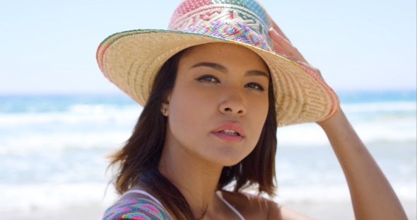 Smiling Young Woman Holding Her Sunhat alt