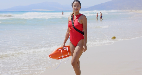 Woman In Lifeguard Outfit On Beach With Swimmers alt