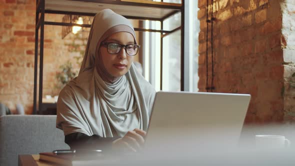Business Lady in Hijab Working on Laptop in Cafe alt