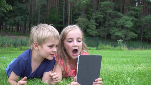 Two Kids Playing With Tablet Outdoors