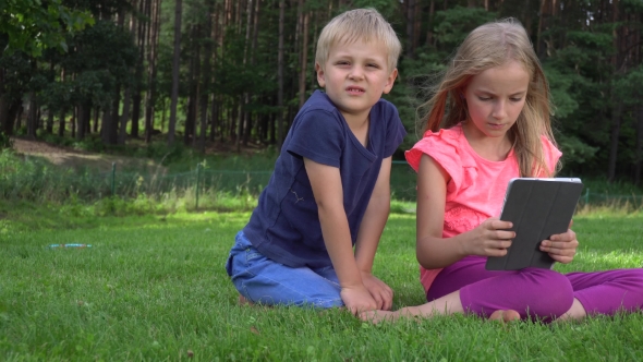 Two Kids Playing With Tablet Outdoors