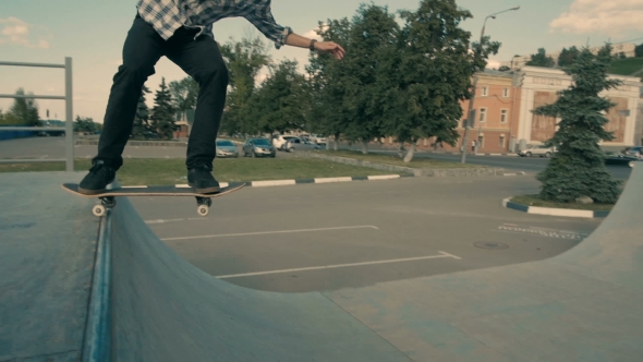 A Skateboarder Defies Gravity As He Rides His Skateboard In An Empty Ramp alt