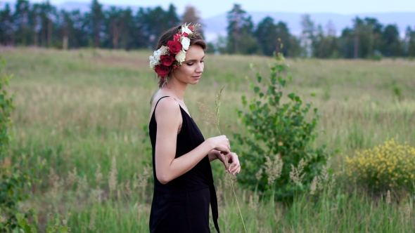 Beautiful Girl in the Black Short Dress With The Wreath on Her Head on the Green Field alt