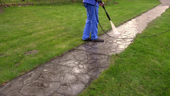 Man Washing Concrete Path With Pressure Washer