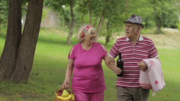 Family Weekend Picnic. Active Senior Old Grandparents Couple in Park. Husband and Wife Walk Together alt