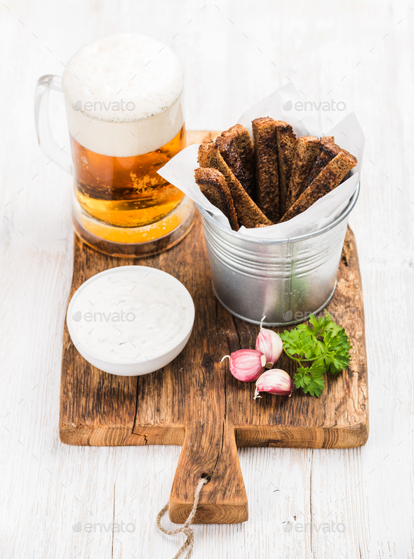 Pint of pilsener in mug, open glass bottle, rye bread croutons - Stock Photo - Images