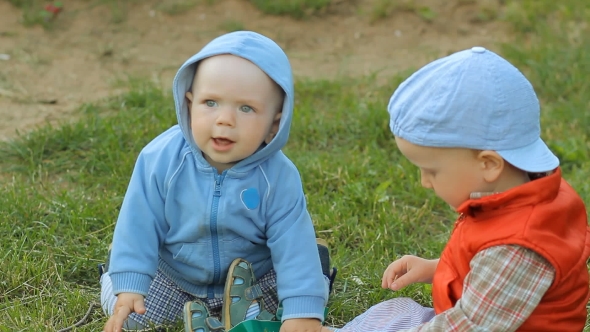 Two Baby Boys Playing Together On The Lawn In The Park