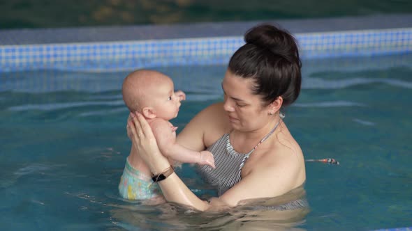 Mother Teaching Baby Boy Swimming in the Pool