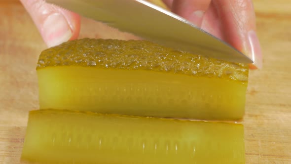 Pickled cucumber cutting on smaller pieces  with knife on wooden board 4K 2160p UHD footage - Gherki alt