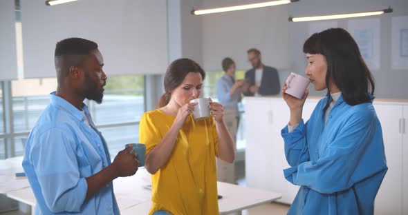 Multiethnic Colleagues on Break Drinking Coffee Chatting in Modern Office alt