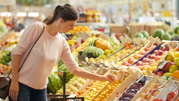 The Girl In a Supermarket Selects The Fruit. alt