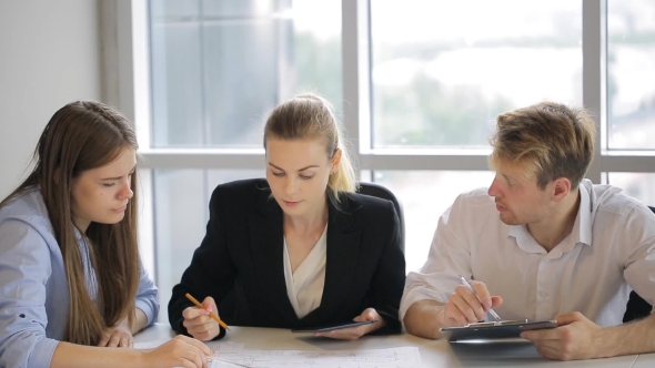 Three People Sit at White Table in the Office