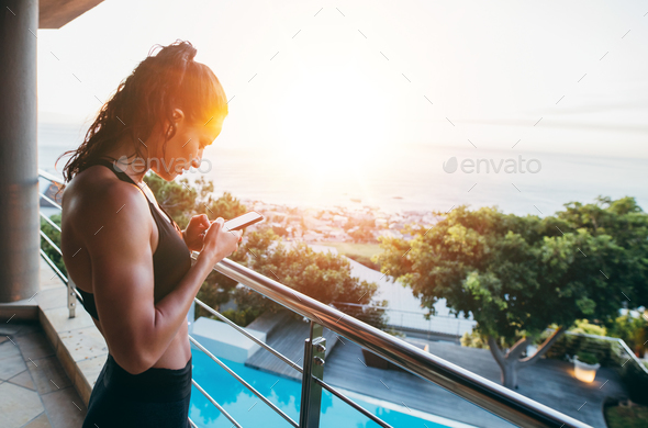 Fitness woman in balcony using mobile phone
