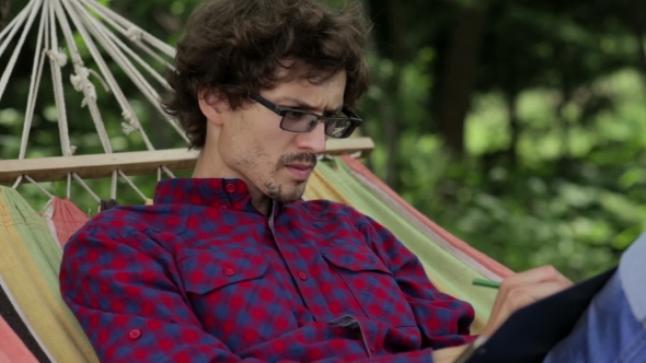 Young Caucasian Man Swinging in a Hammock