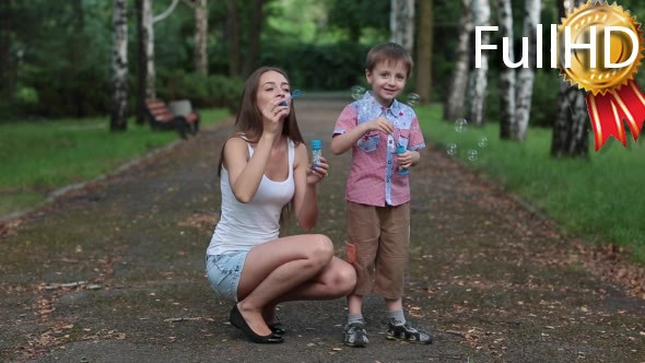 Mother and Son Blow Bubbles in Park