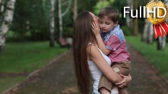 Woman Kisses and Hugs His Son in the Park
