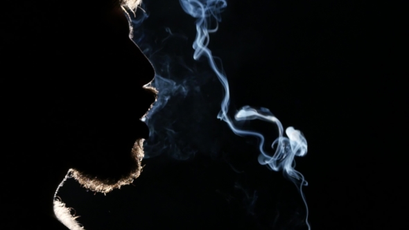 Man Smokes a Cigar. Takes a Big Drag And Puffs Smoke. Blacklight. Silhouette.  alt