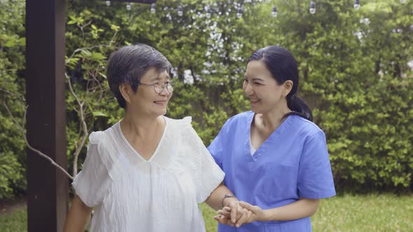 Asian Nurse and Patient Walking in Backyard alt