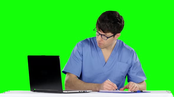 Male Doctor Writing at Desk in His Office Making Prescription. Green Screen alt