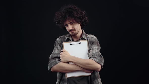 The Portrait of a Charismatic Young Man with Curly Hair Holding the Sheet Support on Which the alt