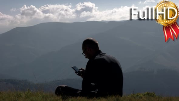 Young Man Using a Mobile Phone on a Mountain Top