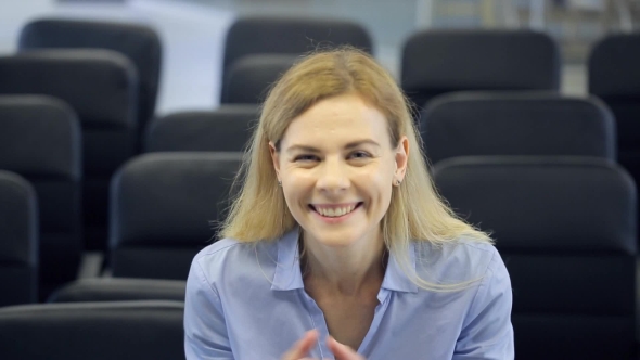 Pretty Blonde Woman Sits In Conference Hall And Cheerfully Claps.