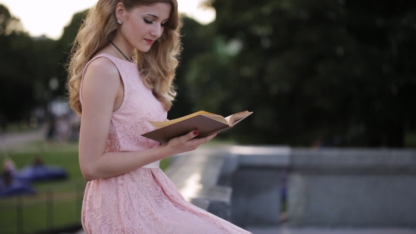 Beautiful Girl Reading a Book In a Park And Dreaming About Love