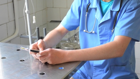 Medical Doctor Sitting At Desk With Phone alt