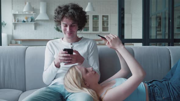 Attractive Couple on Couch with Gadgets Chatting and Messaging alt