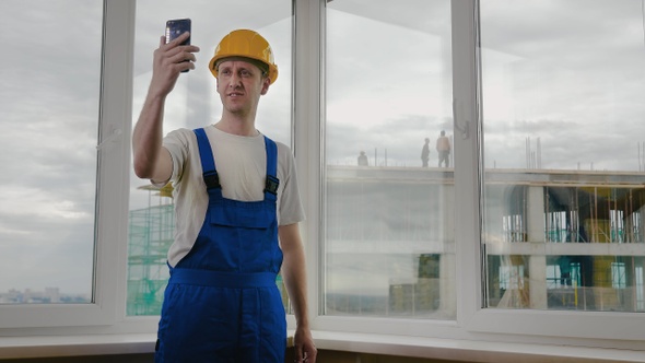 Builders making a selfie with his phone Construction site. alt