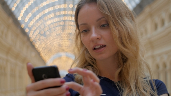 Young Blonde in Casual Style is Taking Selfies by Smartphone and Watching Made Photos