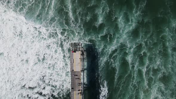Rough ocean waves crashing under a council infrastructure project with tourist sightseeing. High dro alt