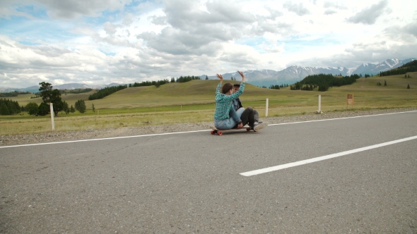 Best Friends Having Fun With Skateboard On Open Road. Young Man And Woman Longboarding Together alt