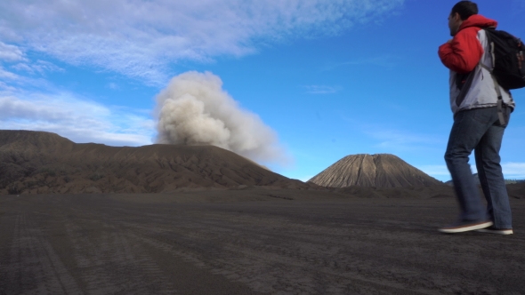 Backpacker Male Traveler Looking At Active Smoking Bromo Volcano In Indonesia alt