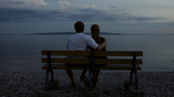 Couple Watching River In The Evening