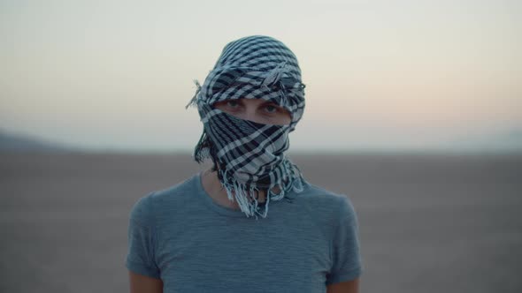 Portrait of Woman Wearing Checkered Keffiyeh Standing in the Desert Looking at Camera alt