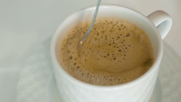 A Person Is Stirring Hot Coffee With a Foam