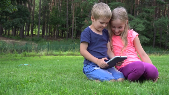 Two Kids Playing With Tablet Outdoors