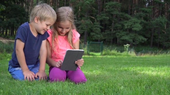 Two Kids Playing With Tablet Outdoors