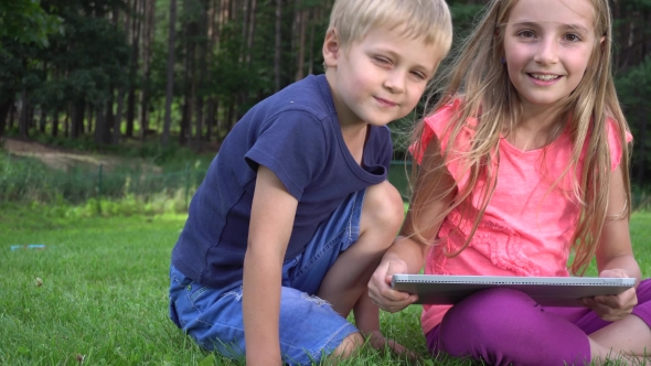 Two Kids Playing With Tablet Outdoors