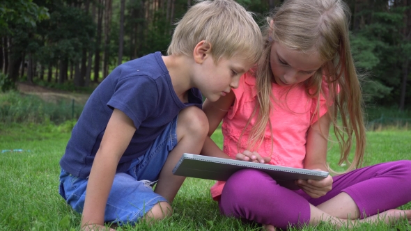 Two Kids Playing With Tablet Outdoors