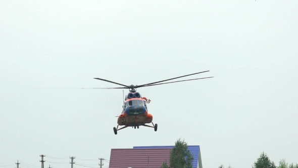 Russia, Novosibirsk, July 31, 2016: Orange Helicopter MI-8 Over The Green Field And Trees.