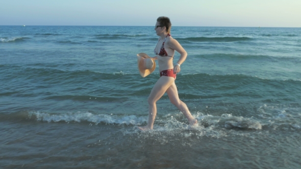 A Female Running In Her Bathing Suit On The Beach