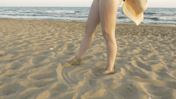 Woman Is Making Imprints On The Sand With Her Feet