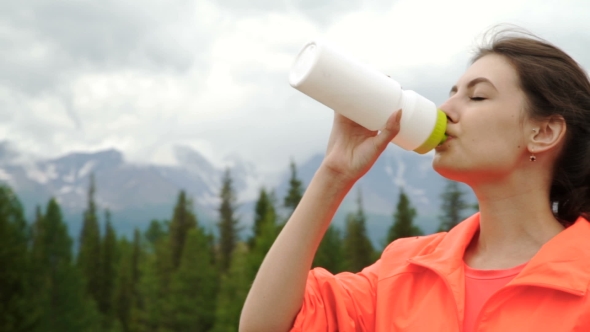 Runner Holding Bottle Of Water While Resting After Evening Jog Outside,