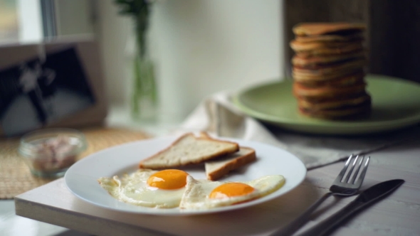 Breakfast Plate. Fried Eggs With Bread Toasts And Pancake Stack On Kitchen Table alt