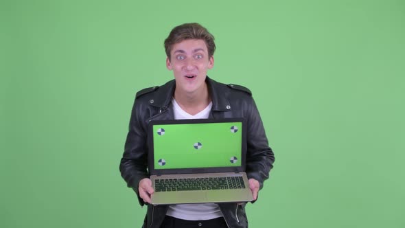 Happy Young Rebellious Man Showing Laptop and Looking Surprised alt