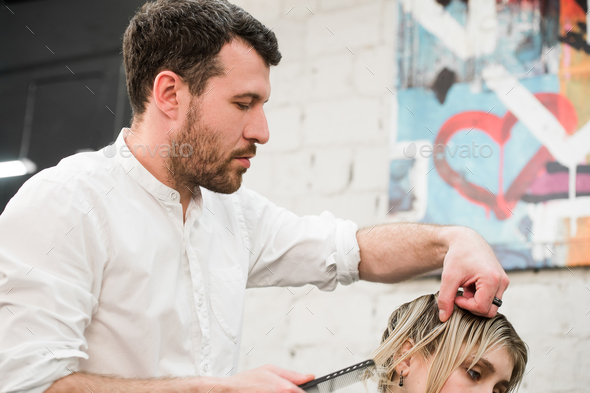 Male Hairdresser Making Haircut For A Client In Professional